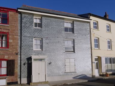 A row of houses with various window styles and a closed door at Nirvana in Kingsand And Cawsand