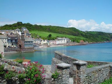 A coastal village with stone buildings next to a bay with green hills in the background at Nirvana Kingsand And Cawsand