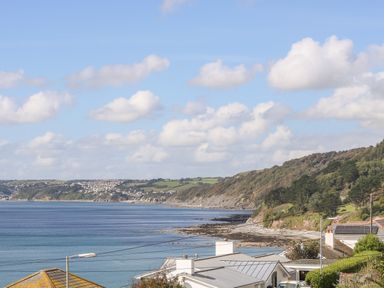 A coastal scene with houses near the shore and hills in the background at Rock Rose in Downderry