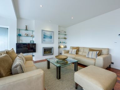 A living room with two beige sofas a glass coffee table and a fireplace at Rock Rose in Downderry