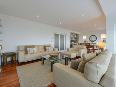 A living room with beige sofas a glass coffee table wooden dining table and chairs at Rock Rose in Downderry