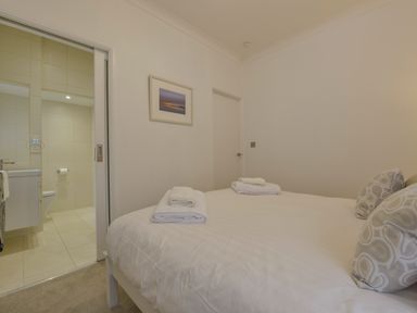 A bedroom with a bed and pillows next to a bathroom at Rock Rose in Downderry