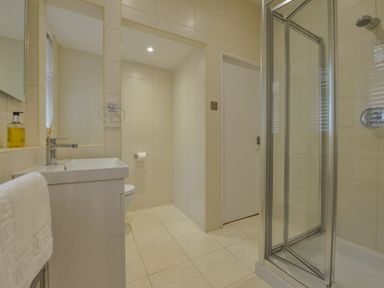 A bathroom with a sink vanity a glass shower enclosure a toilet and a towel rack at Rock Rose in Downderry