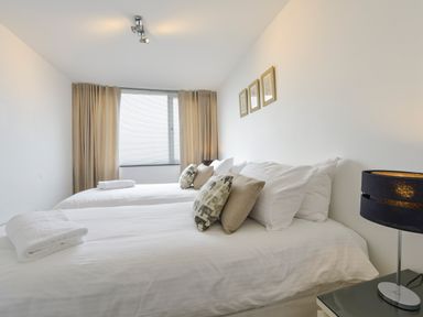 A bedroom with two beds pillows and a lamp on a bedside table at Rock Rose in Downderry