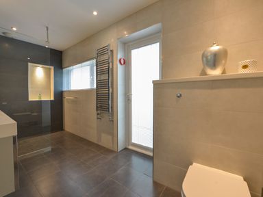 A bathroom with a walk in shower a heated towel rail and a window at Rock Rose in Downderry