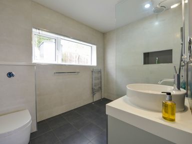 A bathroom with a toilet sink shower area and window at Rock Rose in Downderry