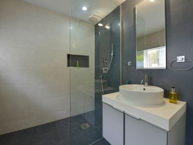 A bathroom with a shower area and a sink on a cabinet at Rock Rose in Downderry