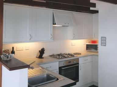 A kitchen with white cabinets a stainless steel sink a gas stove an oven and a microwave at Seagulls Nest in Whitsand Bay near Millbrook