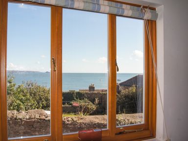 A window with a view of the sea trees and rooftops at Chough Cottage in Kingsand And Cawsand