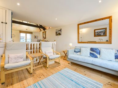 A living room with two armchairs a sofa a large mirror on the wall and a striped rug on the floor at Chough Cottage in Kingsand And Cawsand