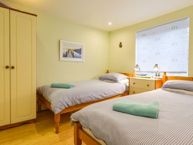 A bedroom with two single beds a wardrobe a chest of drawers and a window at Chough Cottage Kingsand And Cawsand