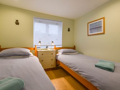 A bedroom with two single beds a small chest of drawers two lamps and a framed picture on the wall at Chough Cottage in Kingsand And Cawsand
