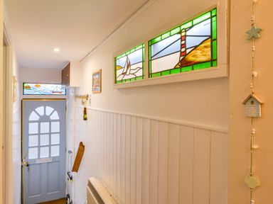 A hallway with stained glass windows above and next to a door at Chough Cottage Kingsand And Cawsand