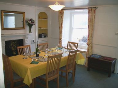 A dining room with a table set with glasses and a bottle at Balcony Cottage in Kingsand And Cawsand