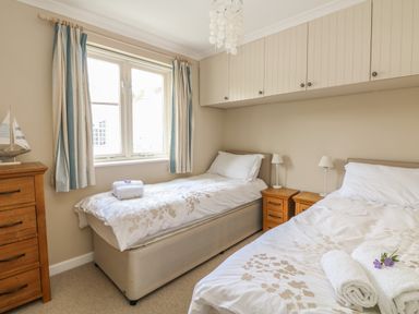 A bedroom with two single beds bedside tables and a wooden chest of drawers at 1 River Cottage Calstock