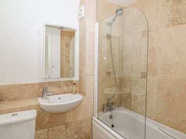 A bathroom with a bathtub shower combination a sink with a faucet a mirror and a toilet at 1 River Cottage in Calstock