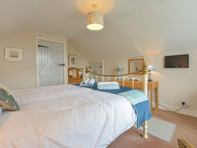 A bedroom with a bed and folded towels on top at Regatta Cottage in Feock