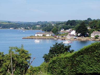 A river with boats and houses along the shore surrounded by trees at Regatta Cottage in Feock