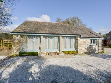 A single story stone cottage with large windows and gravel in front at Hideaway Barn in Charlestown