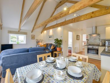 An open plan kitchen and living area with a dining table set with dishes and a teapot at Hideaway Barn in Charlestown