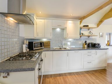 A kitchen with white cabinets gray countertops and wooden floor at Hideaway Barn in Charlestown