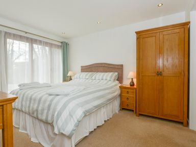 A bedroom with a double bed bedside tables lamps and a wooden wardrobe at Hideaway Barn in Charlestown