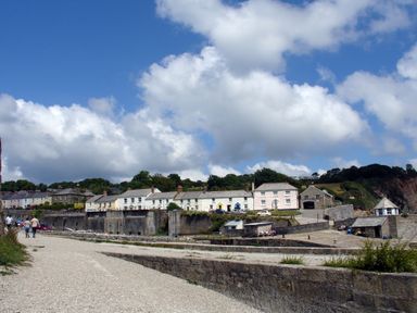A coastal village with stone houses a gravel path people walking and a blue sky with clouds at Hideaway Barn in Charlestown