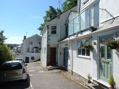 A narrow street with white houses and parked cars in a residential area at Stones Throw in St Mawes