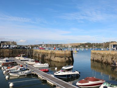 A marina with boats docked along a pier and stone walls surrounding the harbor at Primrose Cottage in Penryn