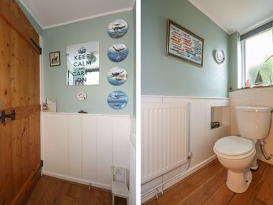 A bathroom with a wooden door wall decorations radiator toilet and a small chair at Primrose Cottage in Penryn