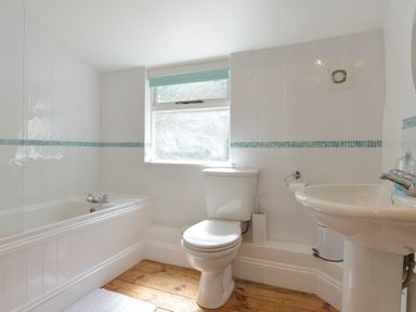 A bathroom with a bathtub toilet and sink at April Cottage in Coverack