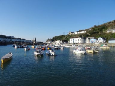 A harbor with boats on water and buildings on a hillside at The Hayloft in Breage