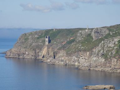 Rocky coastline with three old stone towers overlooking calm sea at The Hayloft in Breage