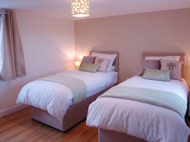 A bedroom with two single beds side by side with pillows and blankets at The Hayloft in Breage