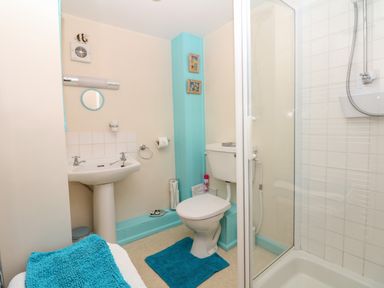 A bathroom with a sink toilet shower and blue towels at Badger Cottage in Mawgan-in-Meneage near Helston