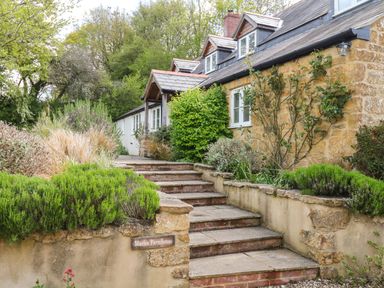 Stone steps leading to a stone and white farmhouse with plants along the pathway at Marles Farmhouse in Salwayash