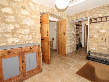 An entrance area with stone walls wooden doors a cabinet a shoe rack and a brown mat at Marles Farmhouse in Salwayash