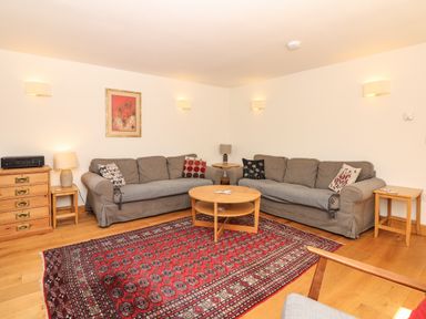 A sitting room with two gray sofas a round wooden coffee table a red patterned rug and wooden side tables at Marles Farmhouse in Salwayash