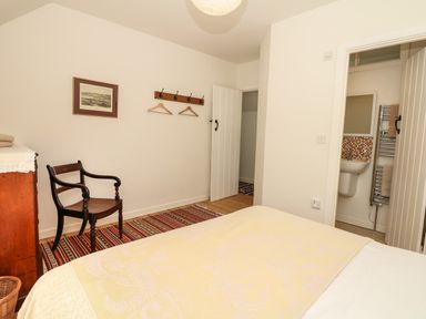 A bedroom with a wooden armchair a dresser and an open door leading to a bathroom at Marles Farmhouse Salwayash