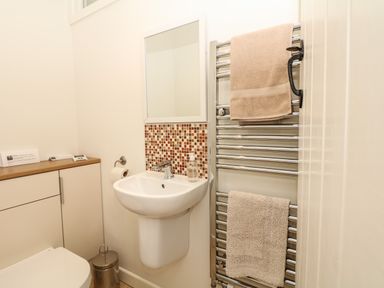 A small bathroom with a sink mirror a toilet a towel rack with towels and a small cabinet at Marles Farmhouse in Salwayash
