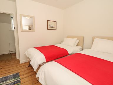 A bedroom with two single beds with red throws a mirror and a framed picture on the wall at Marles Farmhouse in Salwayash