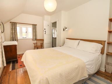 A bedroom with a large bed wooden chair chest of drawers and window at Marles Farmhouse in Salwayash