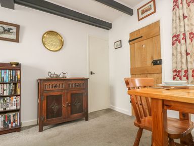 A dining area with wooden furniture a bookshelf and decorative items at Mollys Cottage in St Just