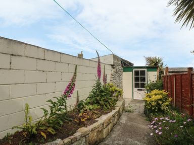 A garden pathway with flowers and plants beside a small shed at Mollys Cottage in St Just