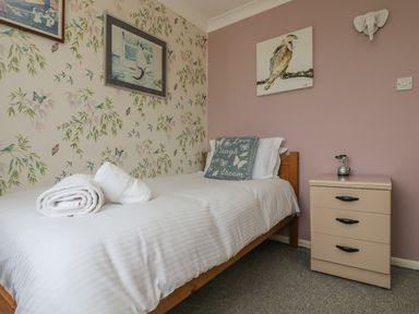 A bedroom with a single bed a pillow a nightstand and wall art at Mollys Cottage in St Just