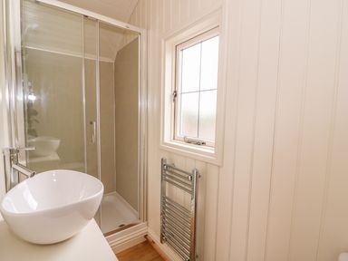 A bathroom with a glass shower enclosure a white vessel sink and a window at Hillside View in Rhayader