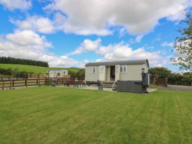 A grassy yard with a small caravan and outdoor seating at Hillside View in Rhayader