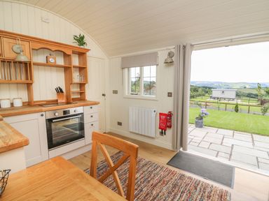 A kitchen with wooden counters, an oven, knives, a plant, and a door opening to a patio and garden at Hillside View in Rhayader
