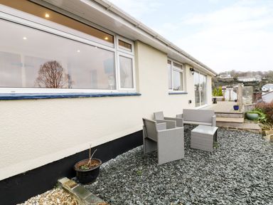 A patio area with outdoor furniture and potted plants outside a house at Treetops Golant near Fowey