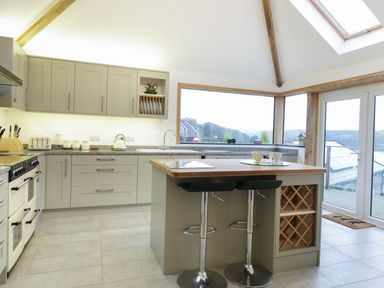 A kitchen with cabinets island and two bar stools at Treetops in Golant near Fowey
